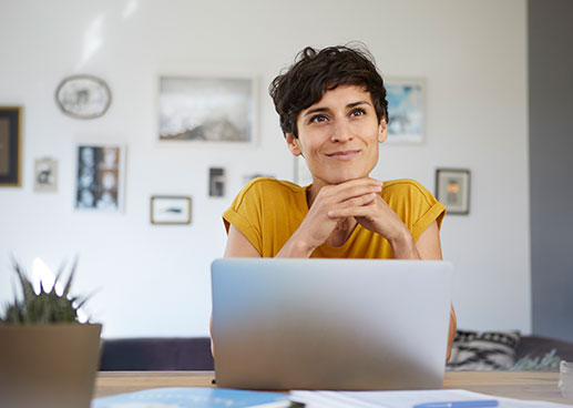 woman in yellow smiling behind laptop