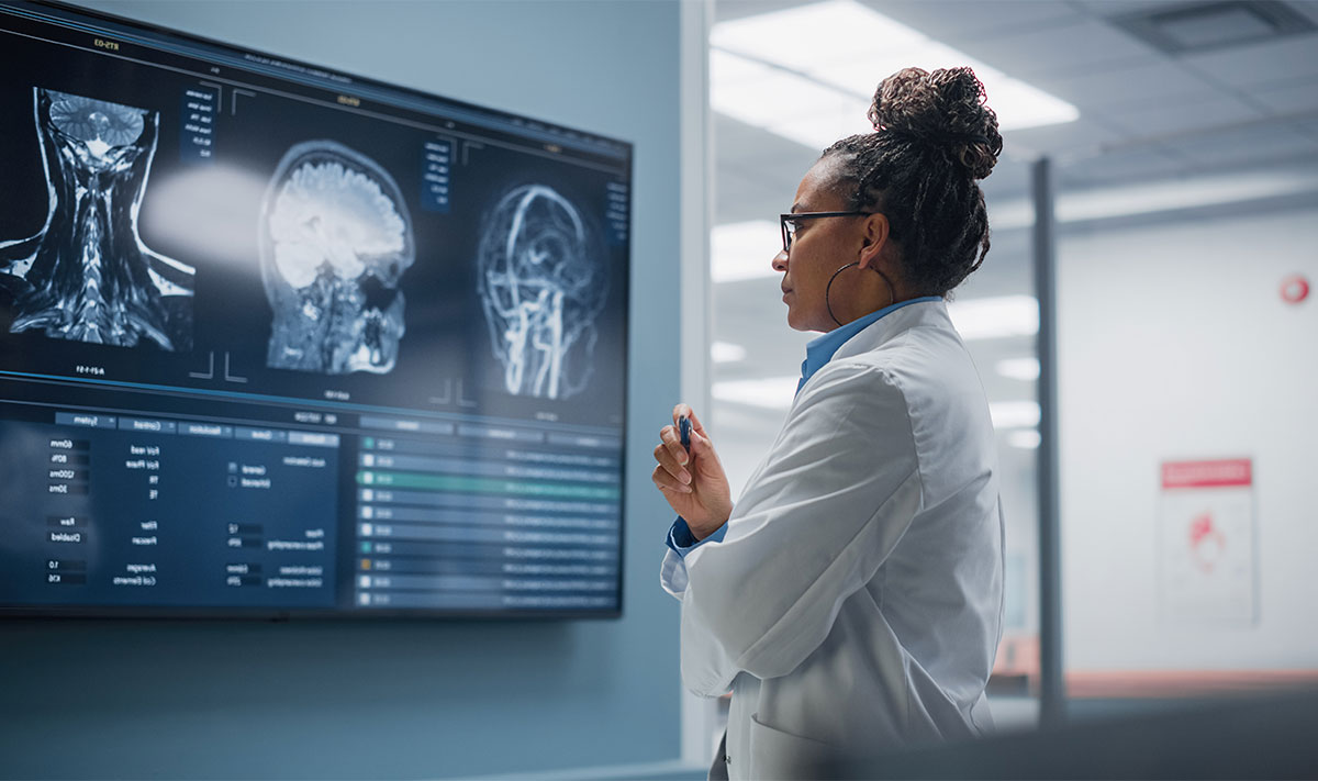 Confident Black Female Neurologist Looks at TV Screen with MRI Scan with Brain Images